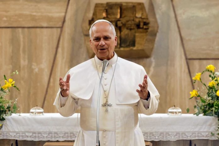 Papa Leão XIV, vestido de branco, discursa num altar decorado com flores amarelas, refletindo o seu apelo à paz durante um evento académico em Roma.