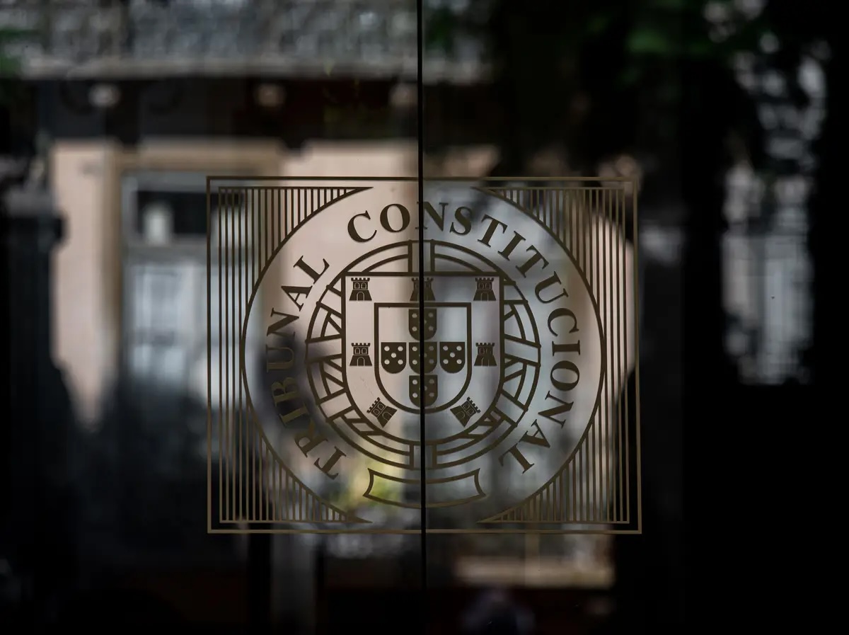 Símbolo e nome do Tribunal Constitucional português numa porta de vidro, representando a instituição que tomou a decisão sobre a lei de imigração e nacionalidade.